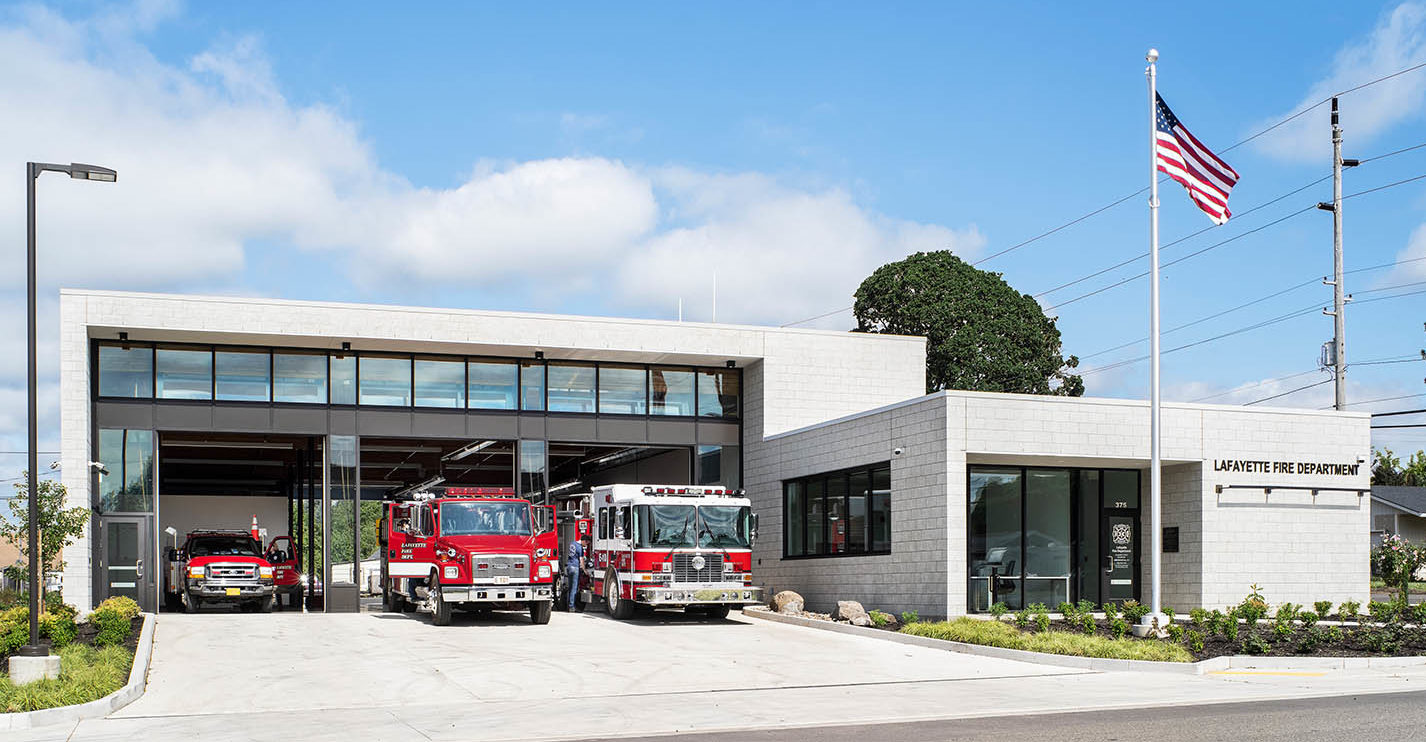 Lafayette Fire Station. Exterior view of fire station with open apparatus bay containing two large fire trucks and an emergency medical vehicle.