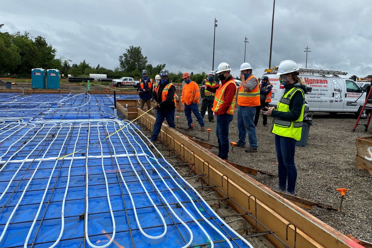 Construction team members review radiant heating tubing installed before the concrete slab pour at the Chemeketa Agriculture Complex.