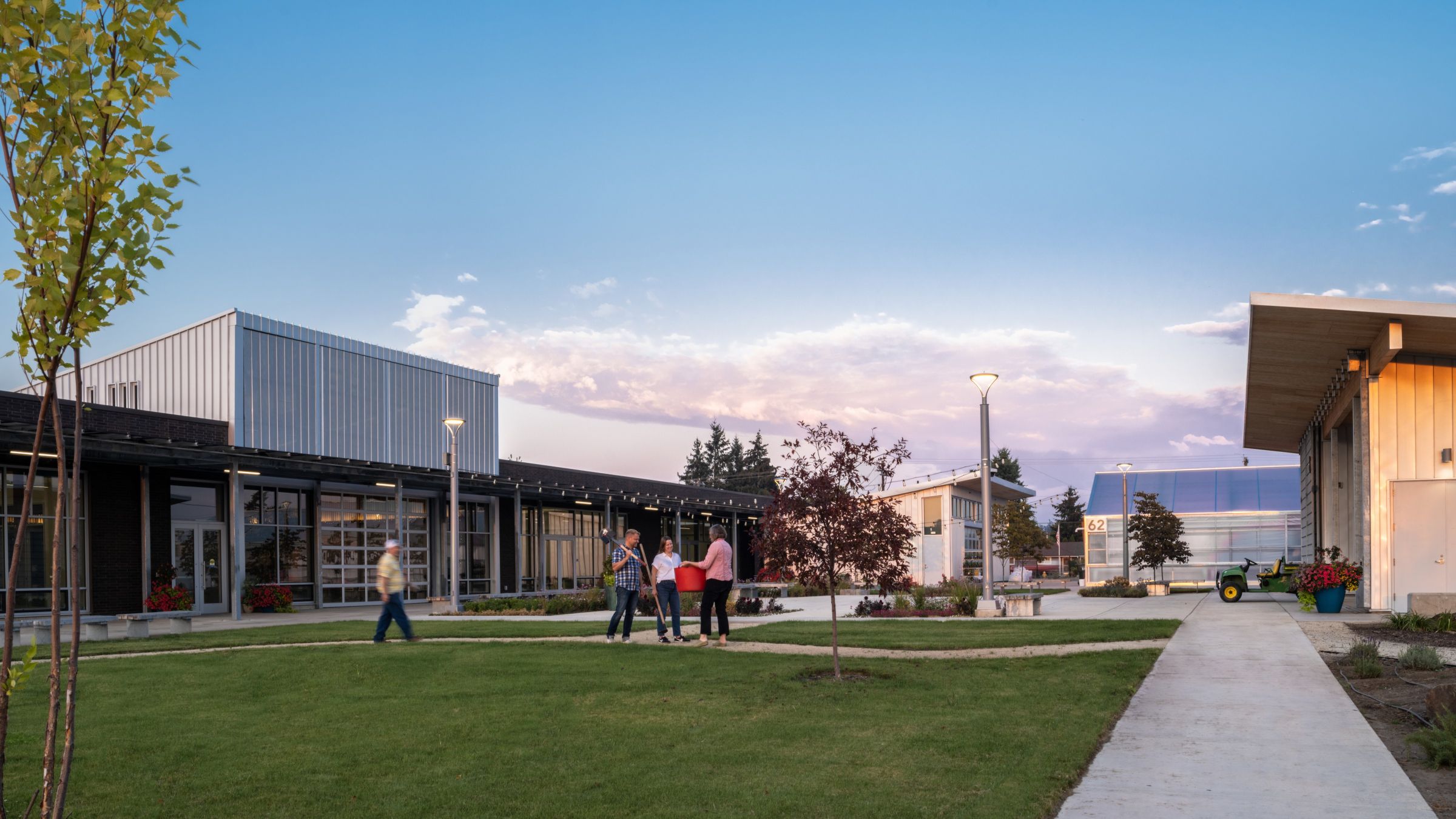 Visitors gather in the landscaped courtyard of the Chemeketa Agriculture Complex, surrounded by teaching buildings, greenhouse space, and outdoor learning areas.
