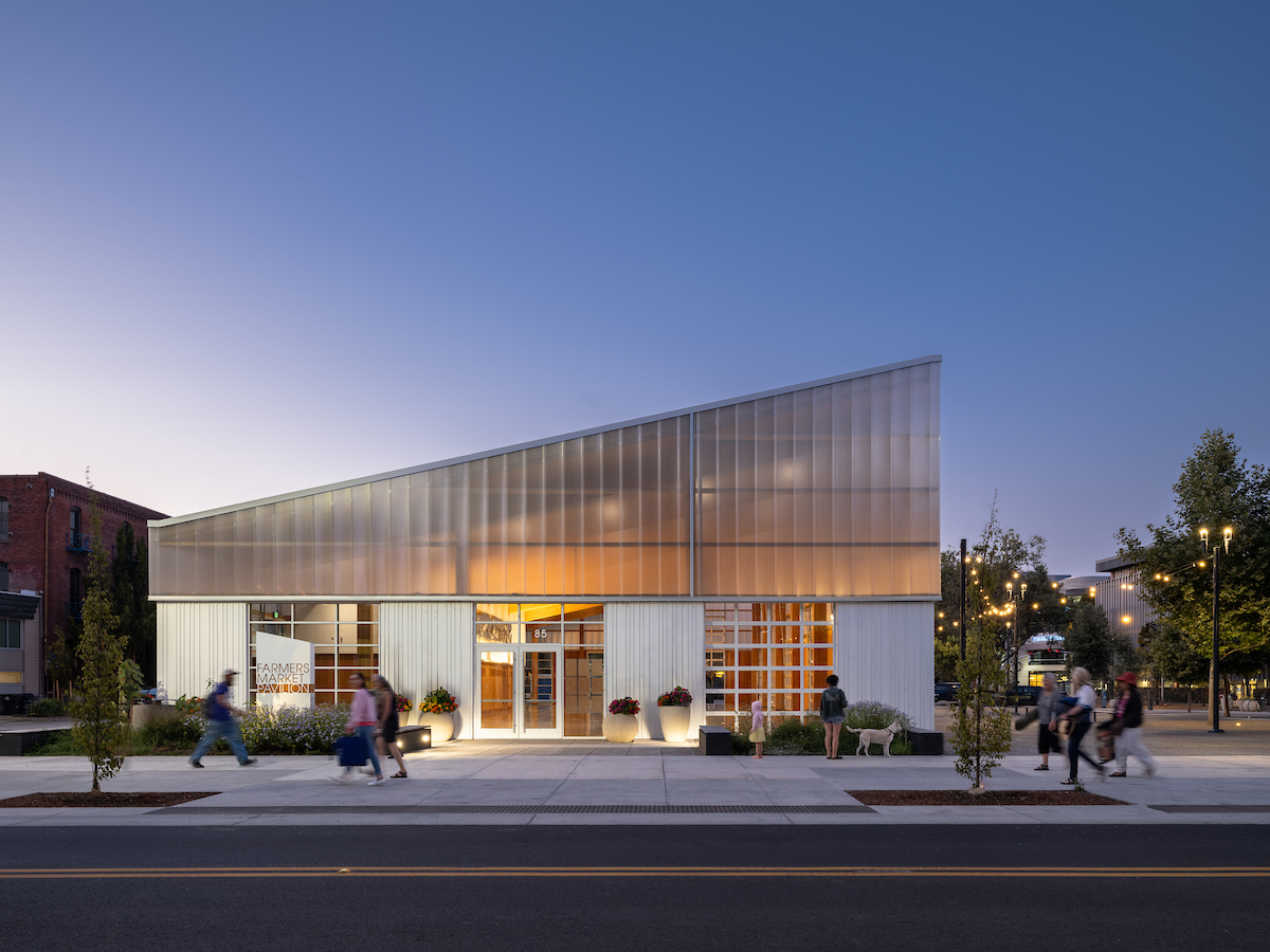 Farmers Market Pavilion at dusk with pedestrians passing by