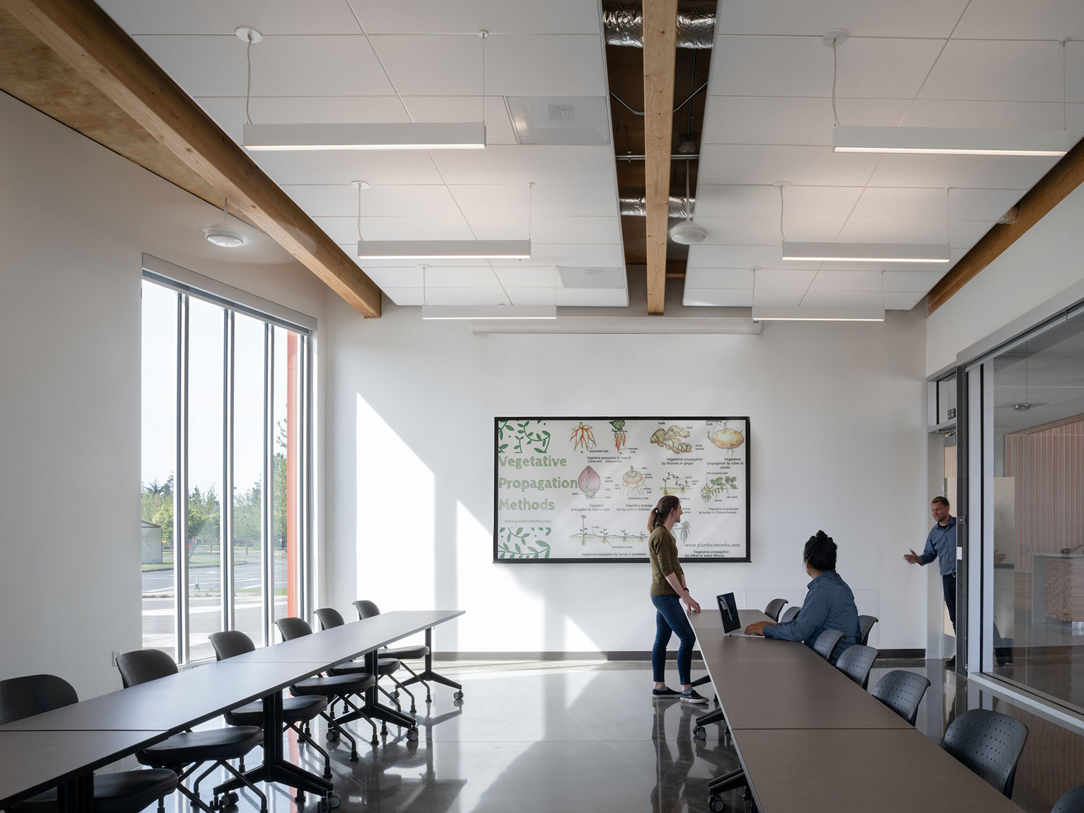 Seminar room with two people inside, and another one entering