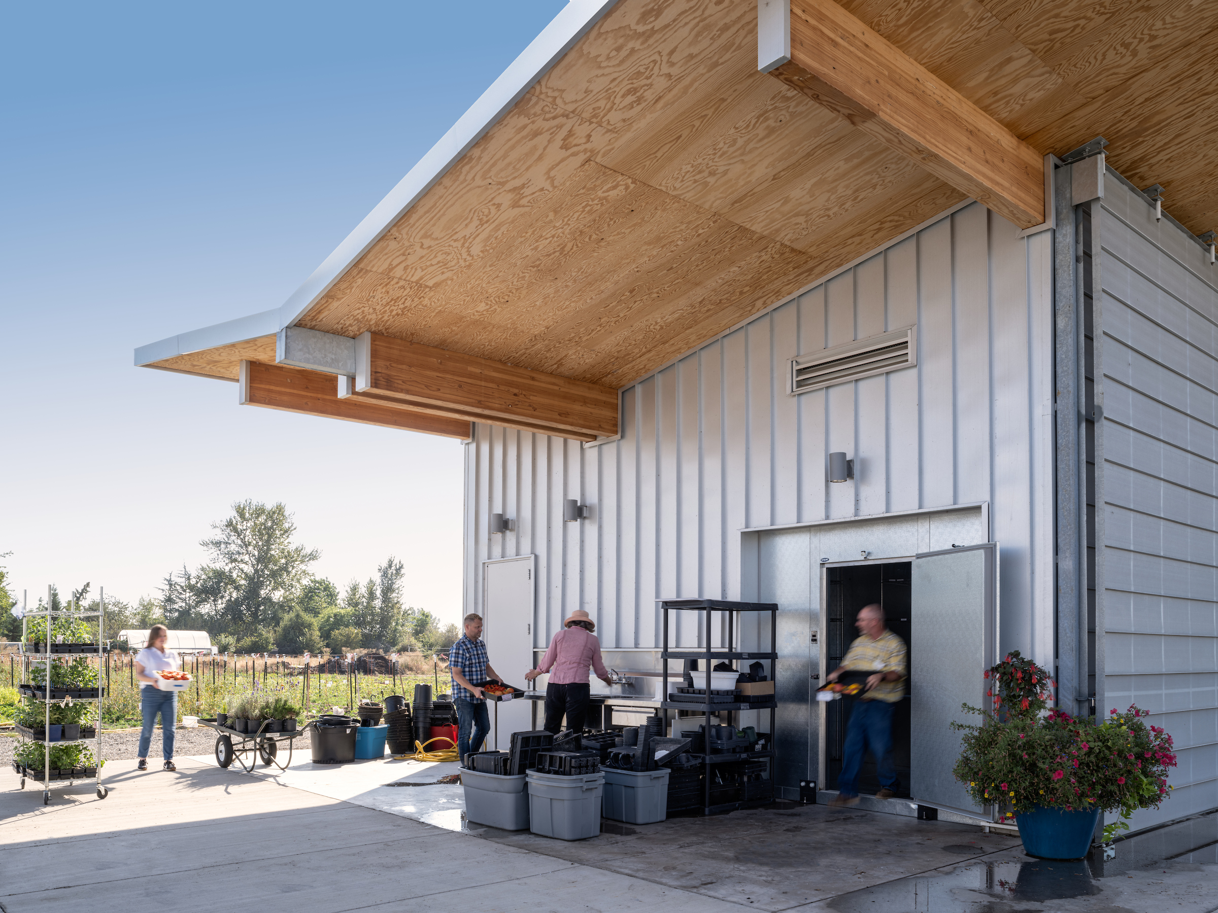 People gardening at outdoor table and sink next to a pavilion building