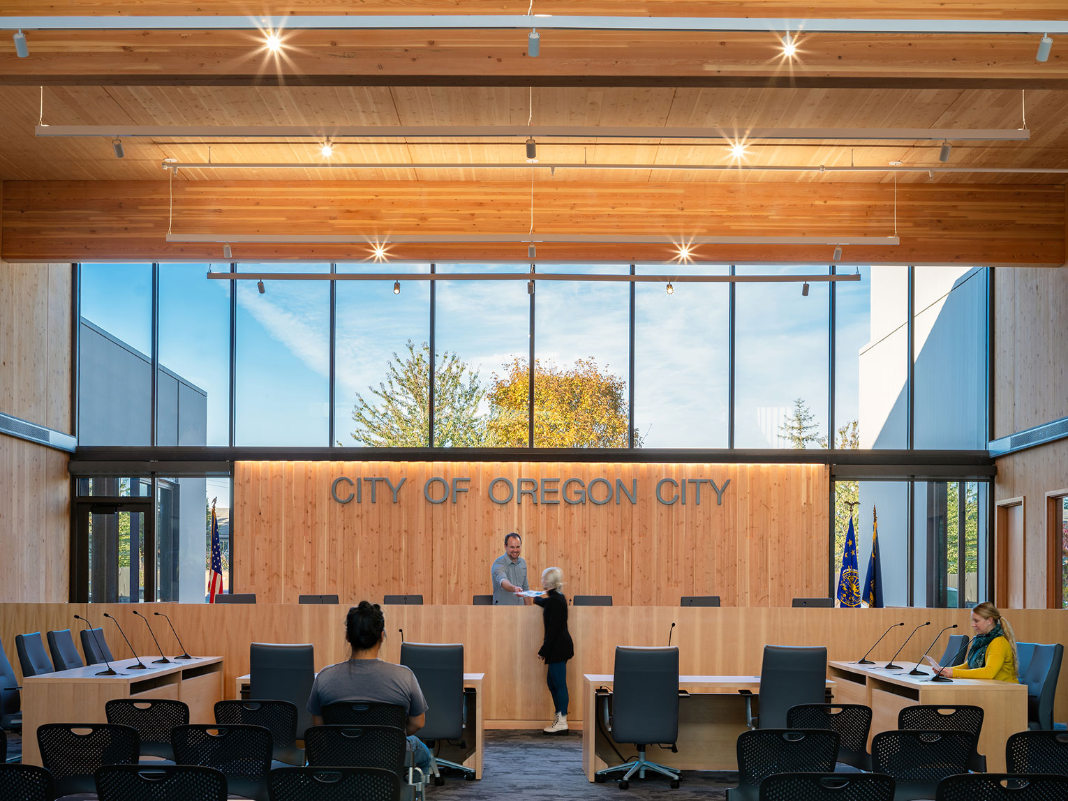 Oregon City Council chambers dias with man handing papers to a woman