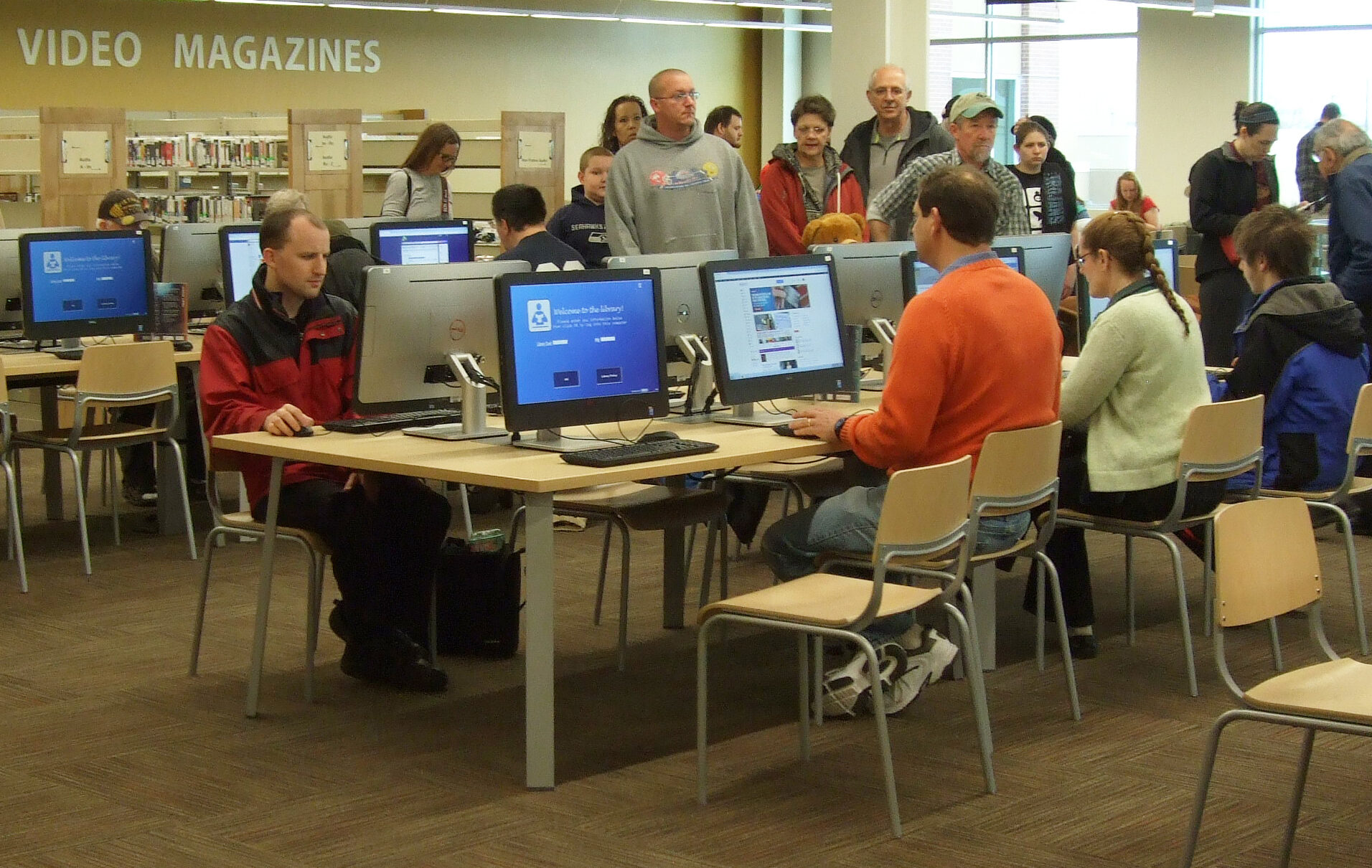 Many members of the public using computers in a library.