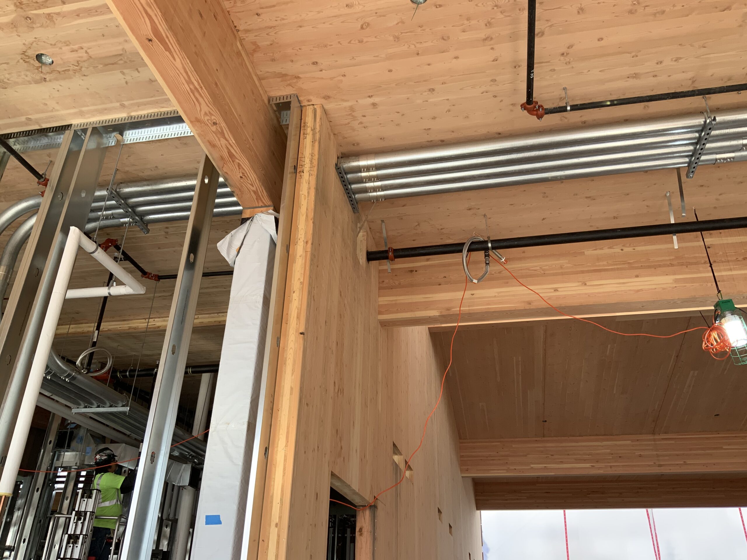 Electrical and plumbing conduits running through a mass timber building under construction