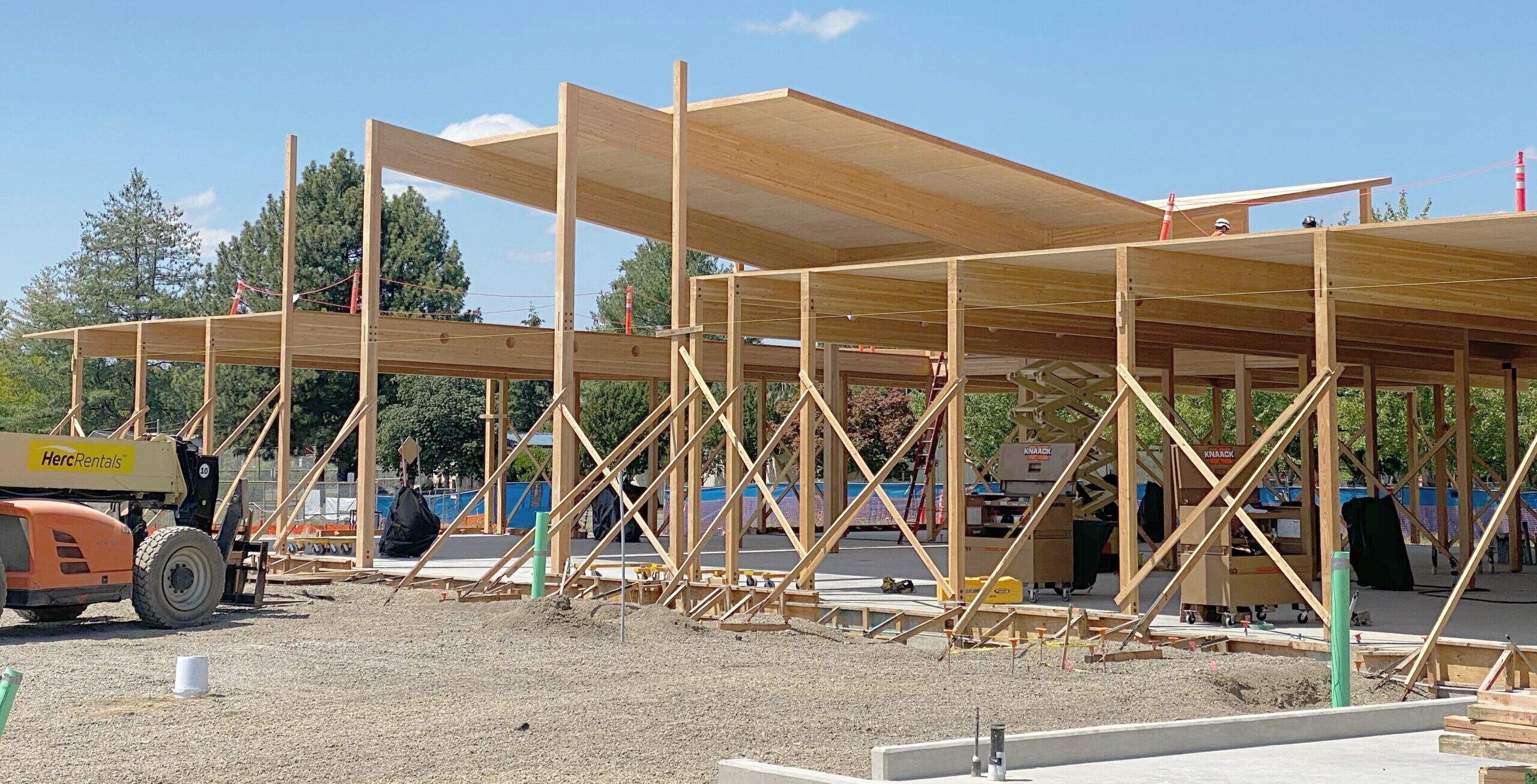 A framed mass timber building under construction on a beautiful blue-sky day