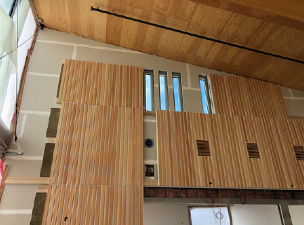 Custom mass timber-covered acoustical panels being installed in a building under construction
