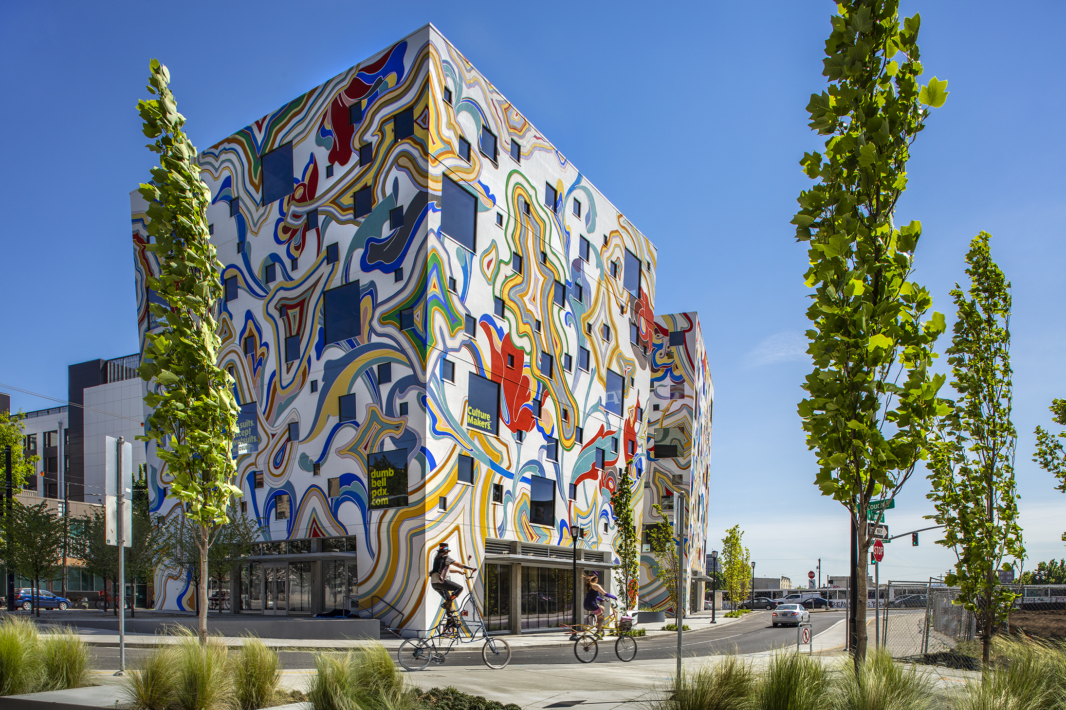 A three story building with an exterior featuring a multi-colored mural