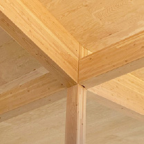Detail of a mass timber ceiling where mass timber support beams converge from four directions and are supported by a mass timber column