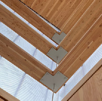 An upside down image of mass timber roof support beams connected at the apex with steel plates