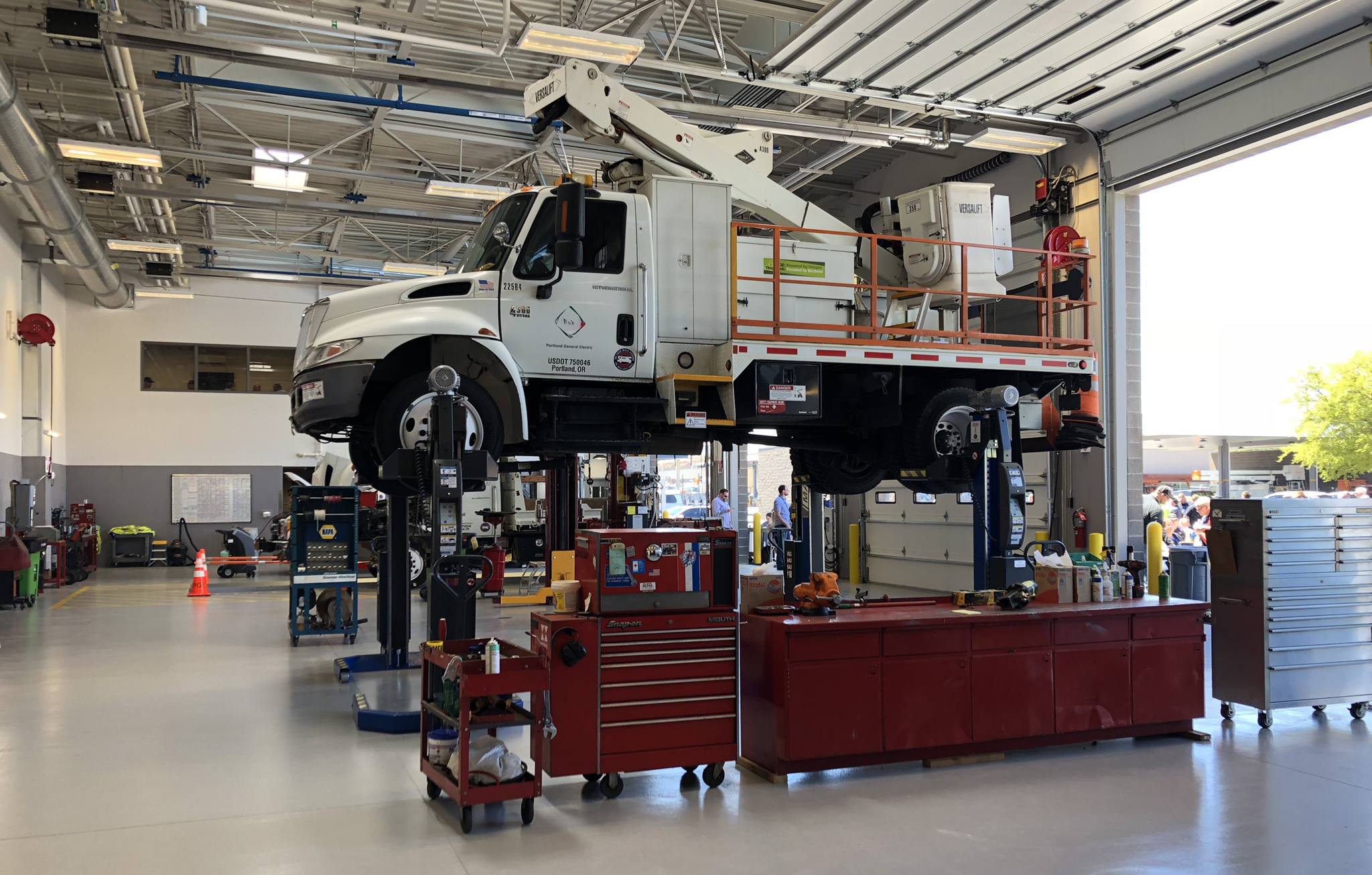 Interior image of a maintenance garage with a utility truck on a lift, and garage doors rolled up 