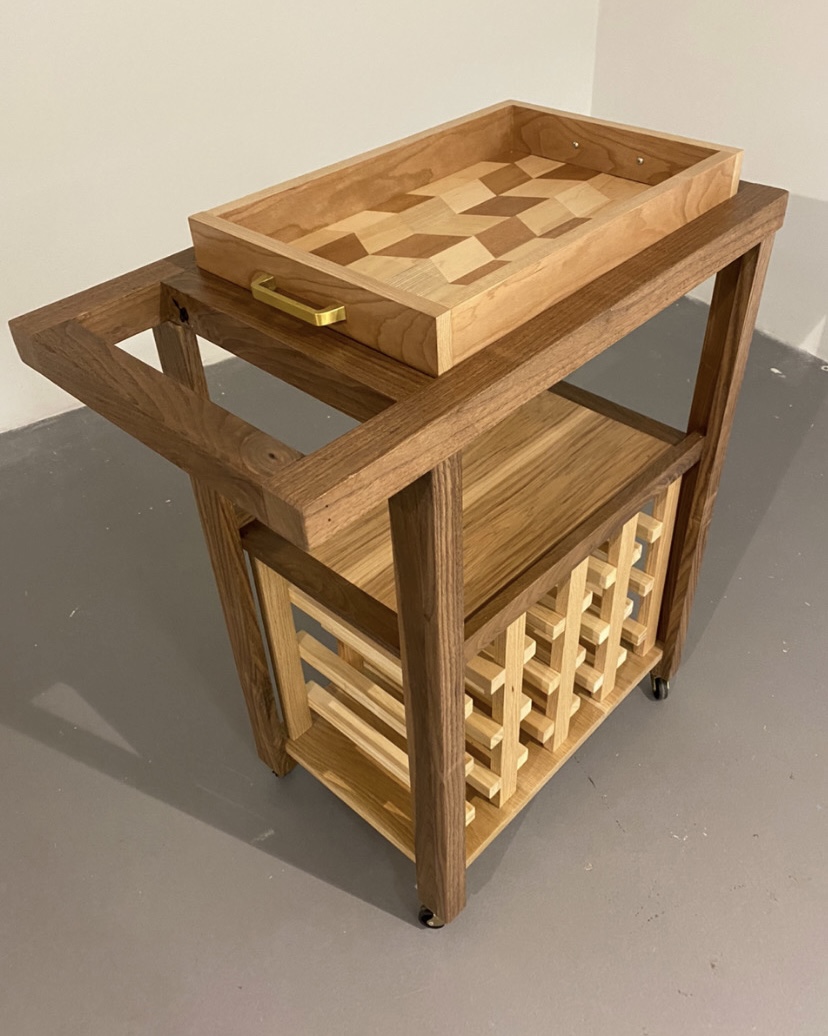 A sleek wooden bar cart with an inlayed tray on top and wine rack underneath.