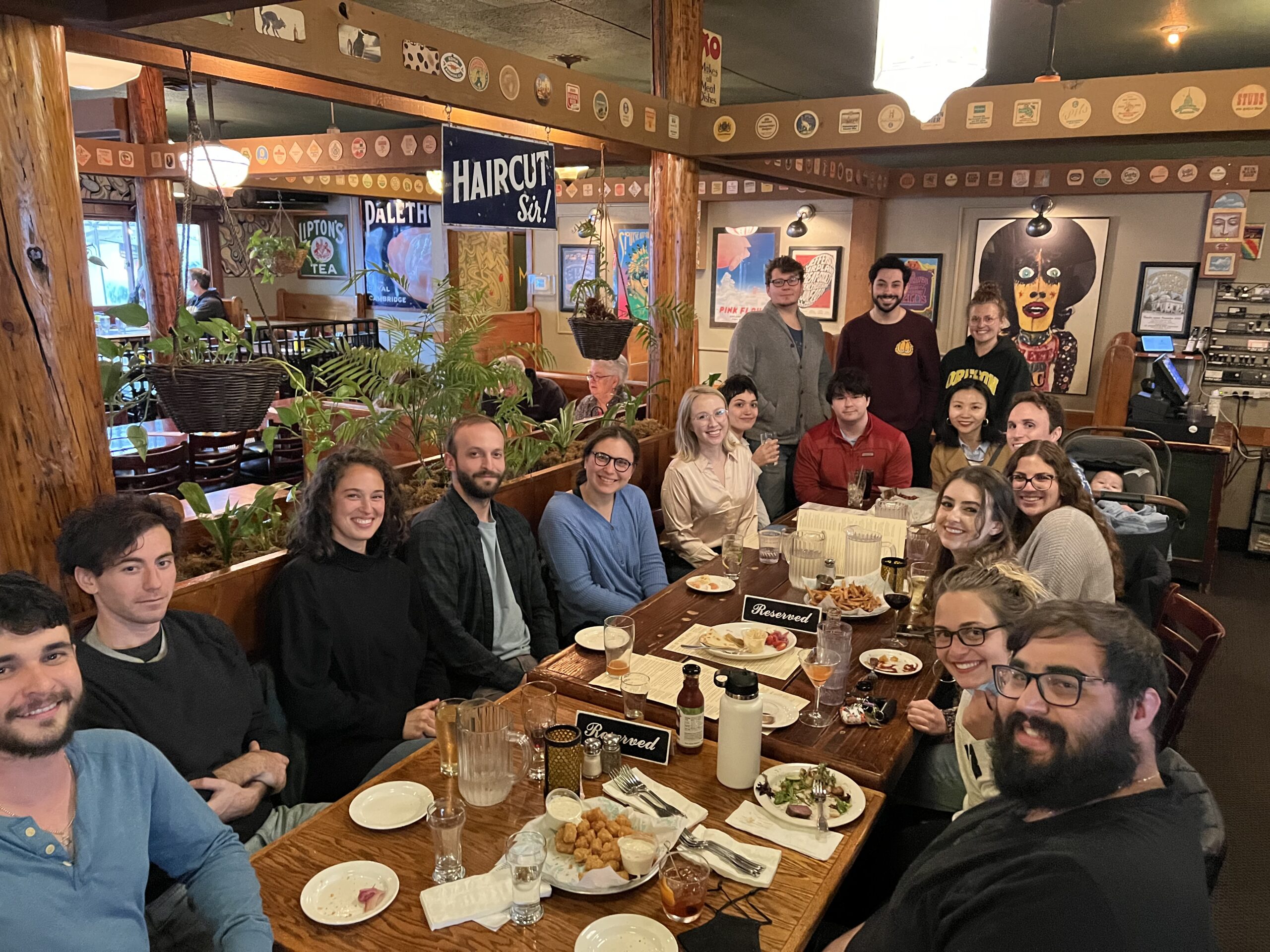 A group of young adults sitting around a restaurant table, happily enjoying a meal..