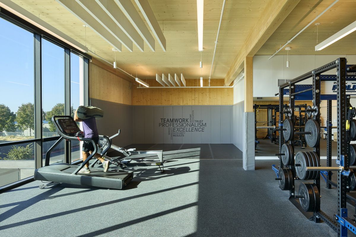 A police officer trains in the light-filled fitness room at the Redmond Public Safety Facility, with mass timber and strength equipment.