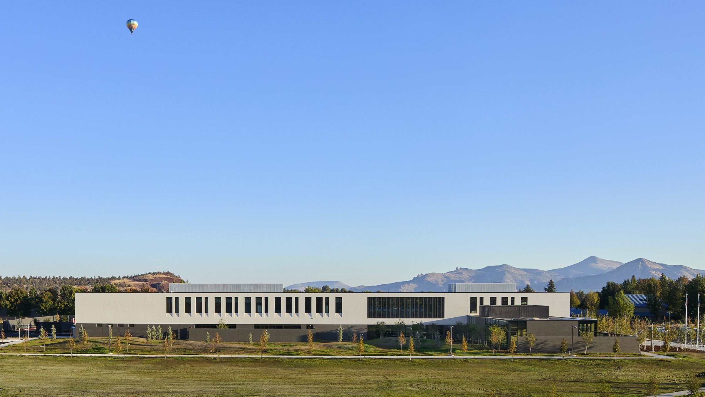 The Redmond Public Safety Facility sits against the Central Oregon landscape, with mountain views and a hot air balloon overhead.
