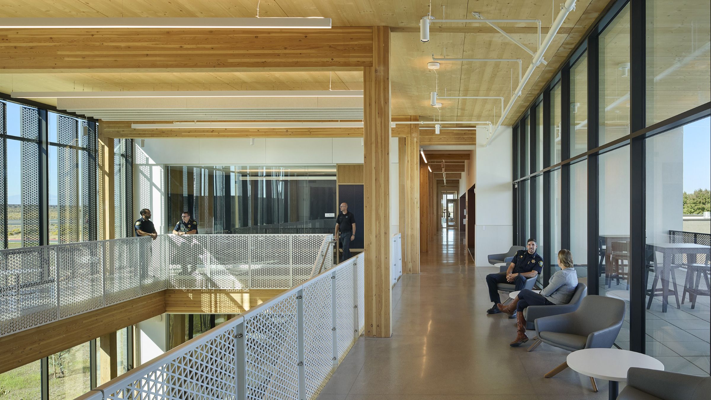 Police staff gather along the second-floor hub of the Redmond Public Safety Facility, surrounded by exposed mass timber and expansive glazing.