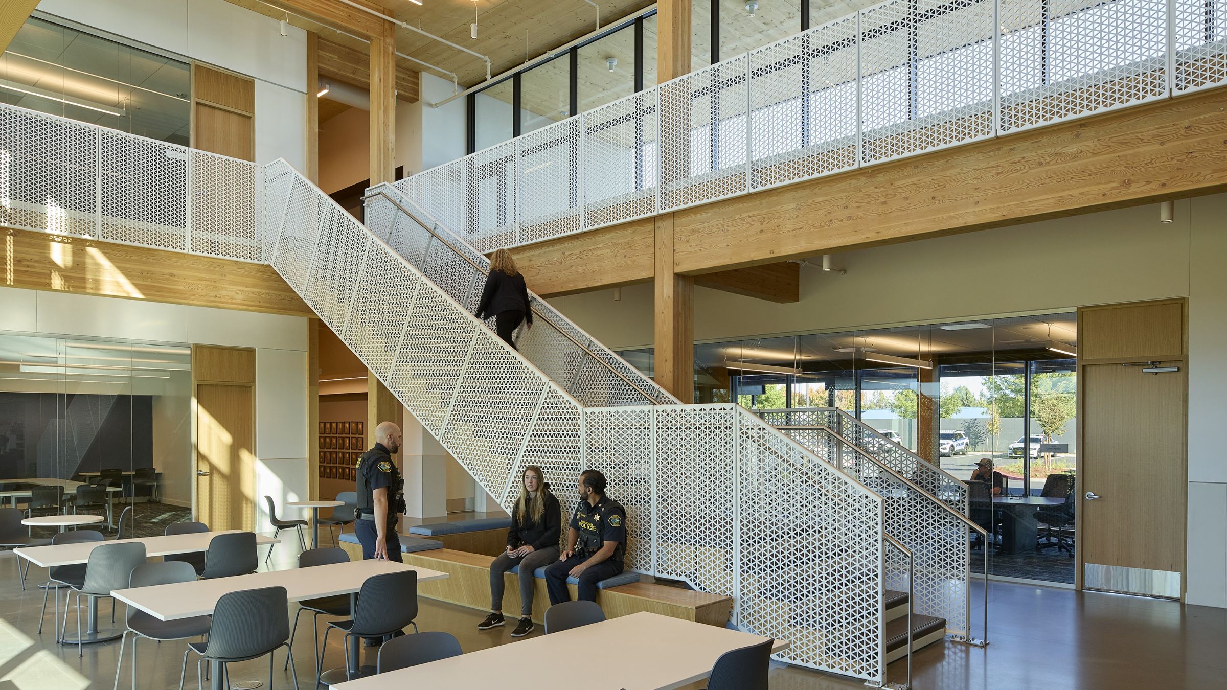 Police staff gather in a light-filled central hub at the Redmond Public Safety Facility, framed by mass timber and an open stair.
