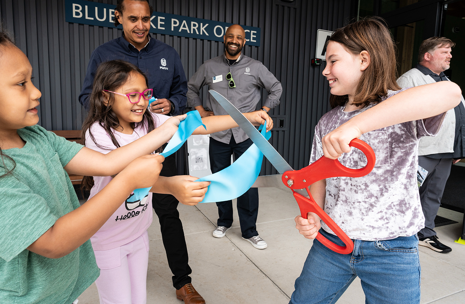 Children cut a ribbon at the Blue Lake Park Office opening as community leaders look on