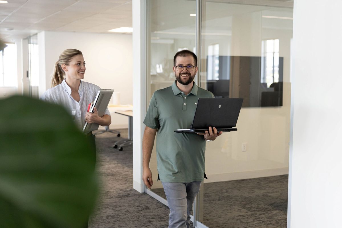 Two FFA team members carry laptops while walking through the firm’s bright, collaborative architecture studio.