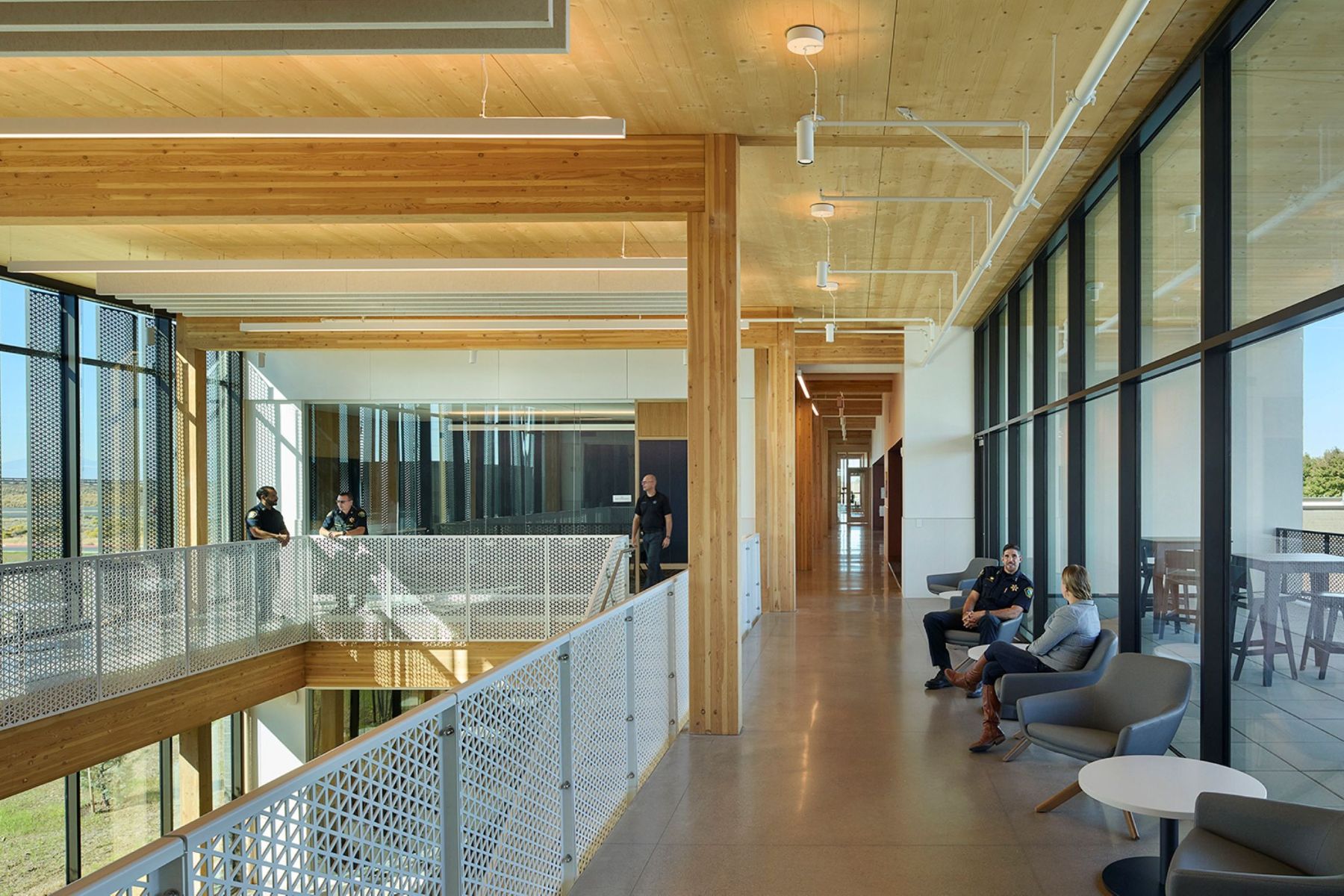 Officers and staff gather along a light-filled second-floor corridor at the Redmond Public Safety Facility, framed by exposed mass timber and expansive glazing.