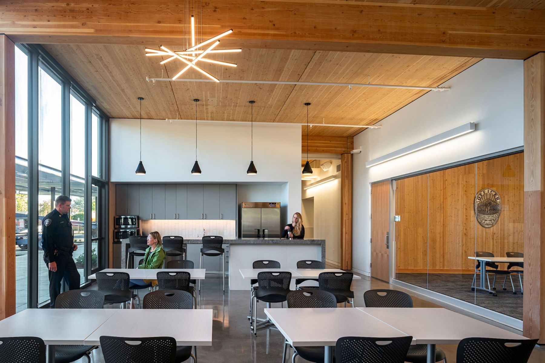 Police staff use a light-filled break room at the Robert Libke Public Safety Building, framed by exposed mass timber and flexible seating.